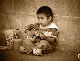 坐在地上弹吉它的小男孩